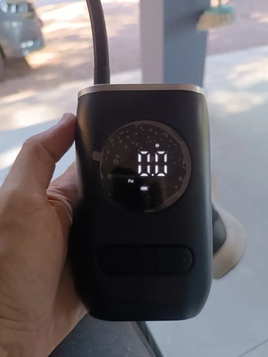Compressor compacto segurado na mão, próximo a uma janela